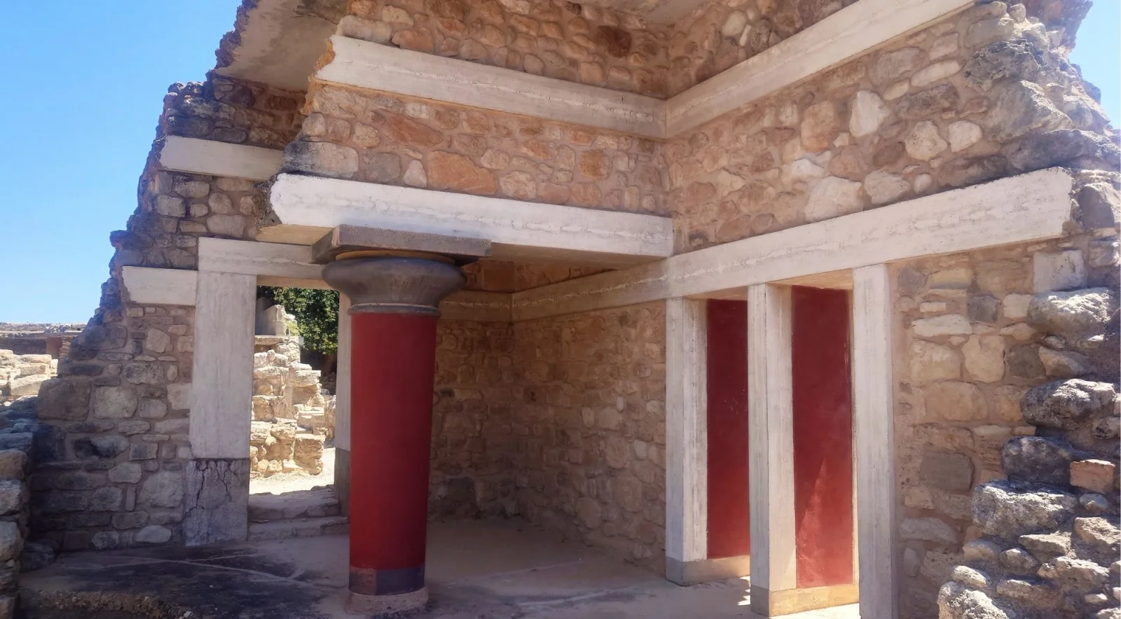 Restored interior room at Knossos with red columns, stone walls and open doorways