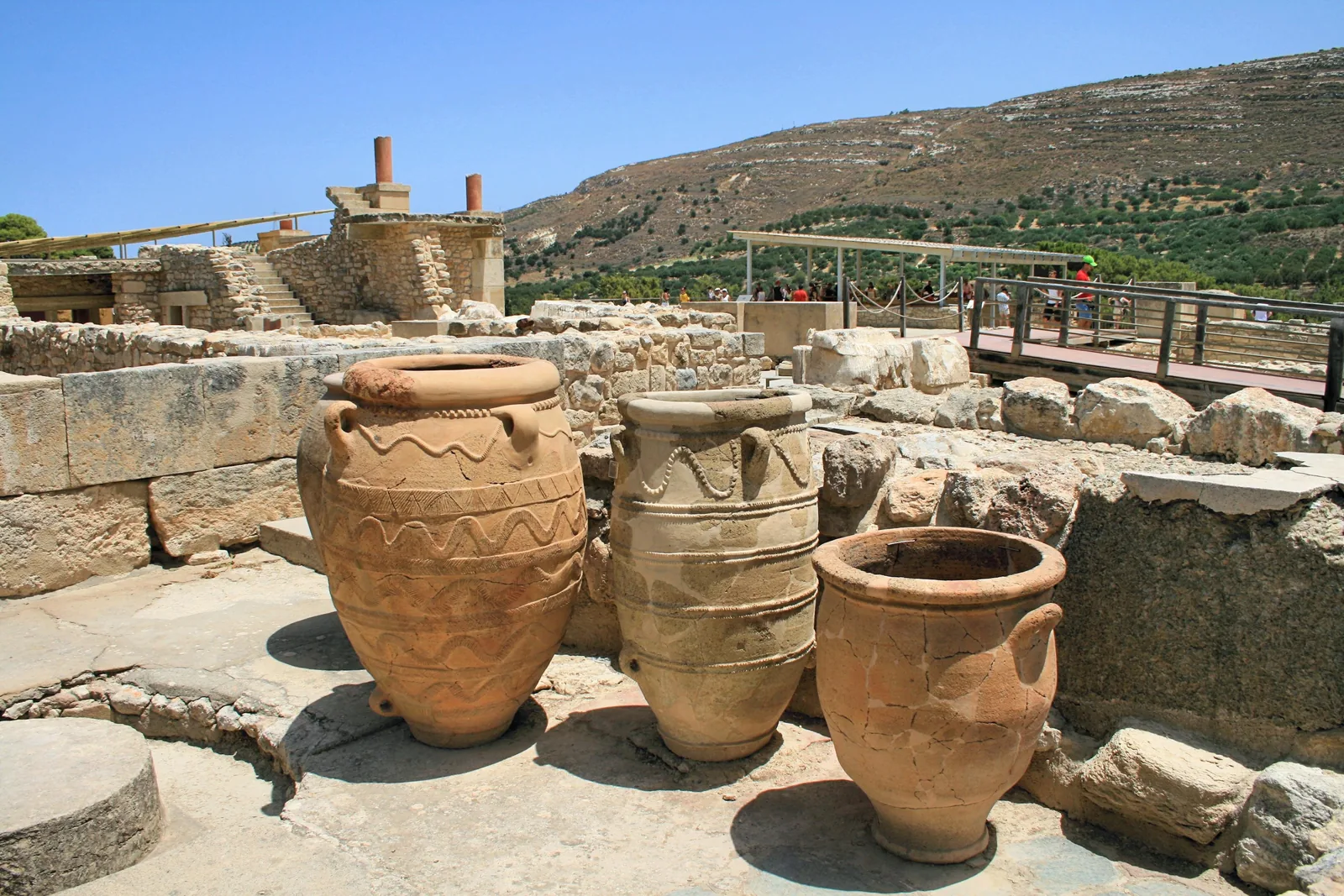Large Minoan storage pithoi standing among the excavated ruins at Knossos