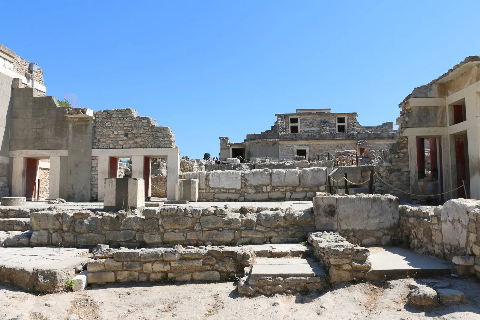 Low stone walls and red-columned rooms across the residential quarter of Knossos