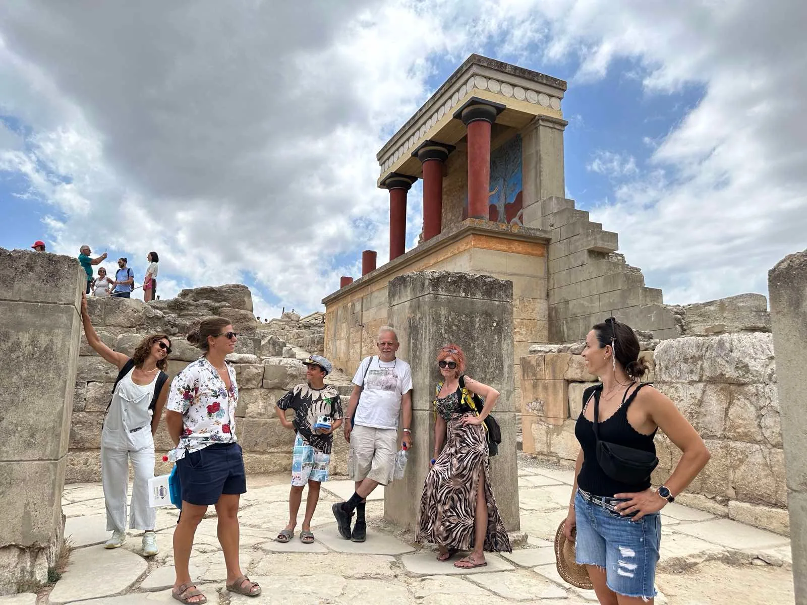 Tour group gathered beneath the restored North Entrance bastion at Knossos under a cloudy sky