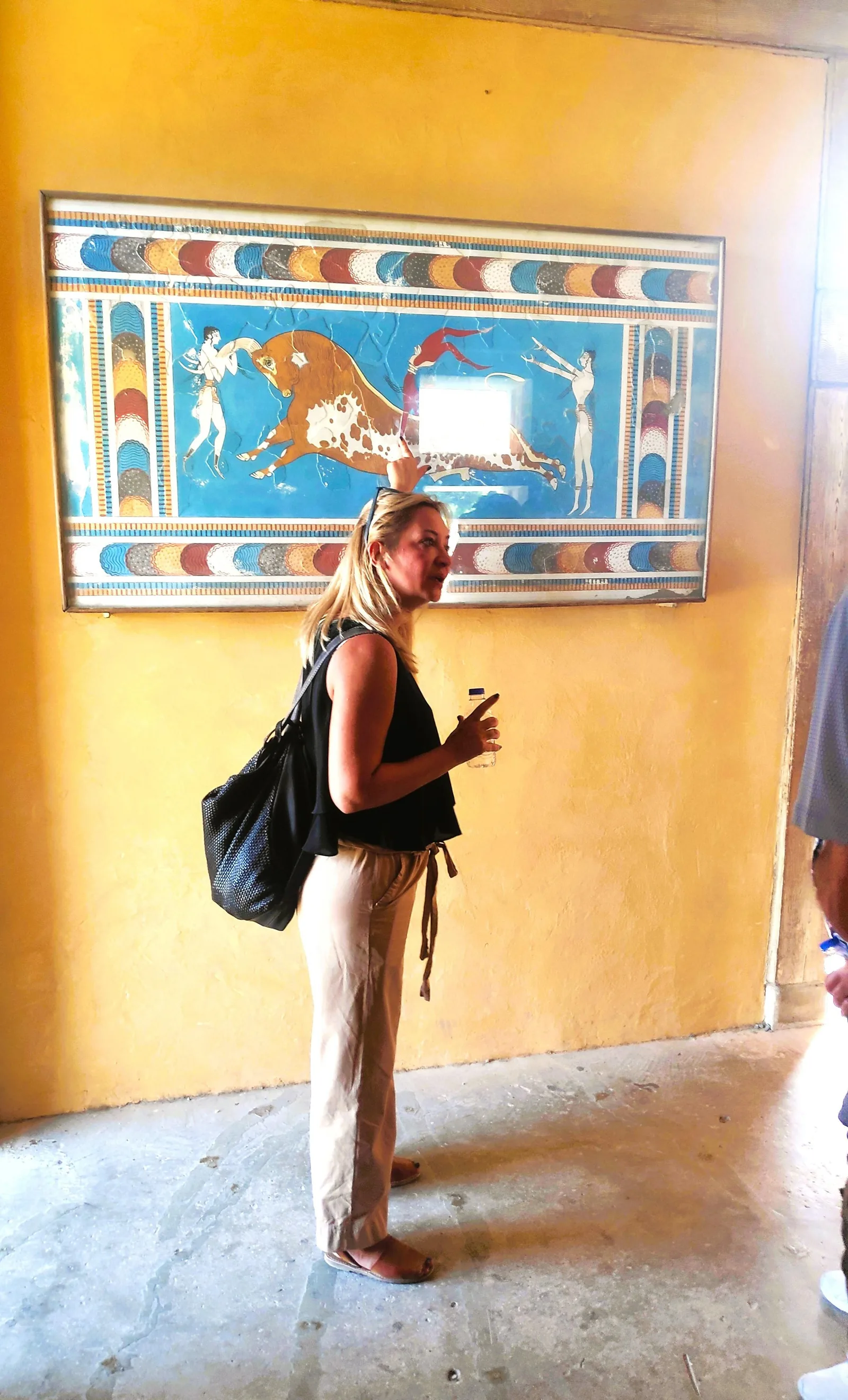 A performer in Minoan costume in front of a reproduction of the bull-leaping fresco