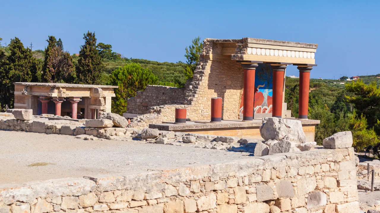 The long restored facade of Knossos above rough excavated walls, with the Cretan hills behind