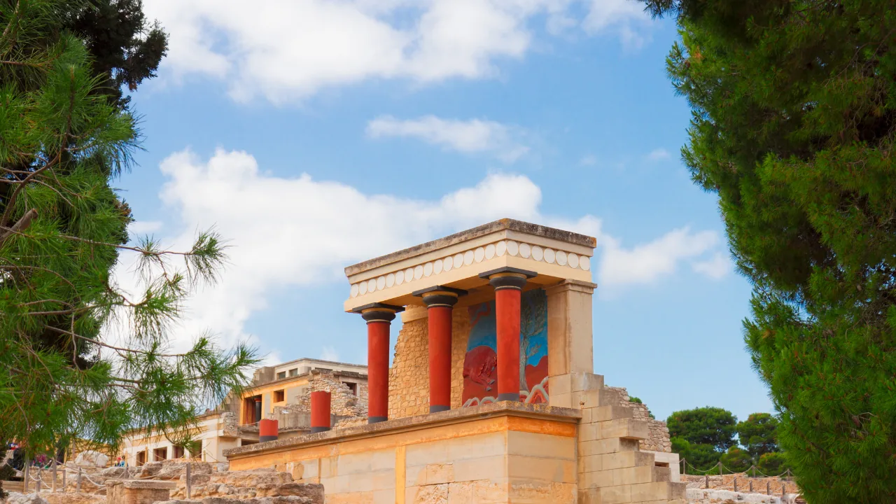The restored portico and red columns at Knossos framed by pine trees