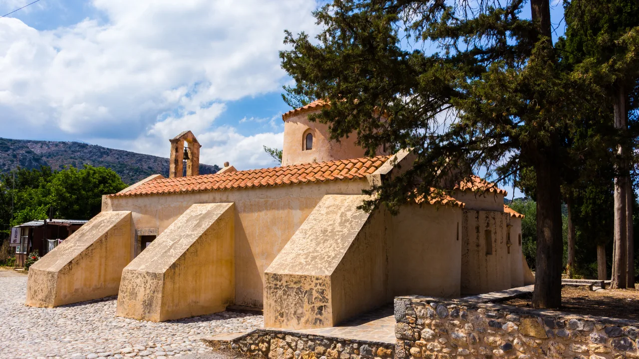 The stone church of the Vidiani Monastery on Crete, shaded by pine trees